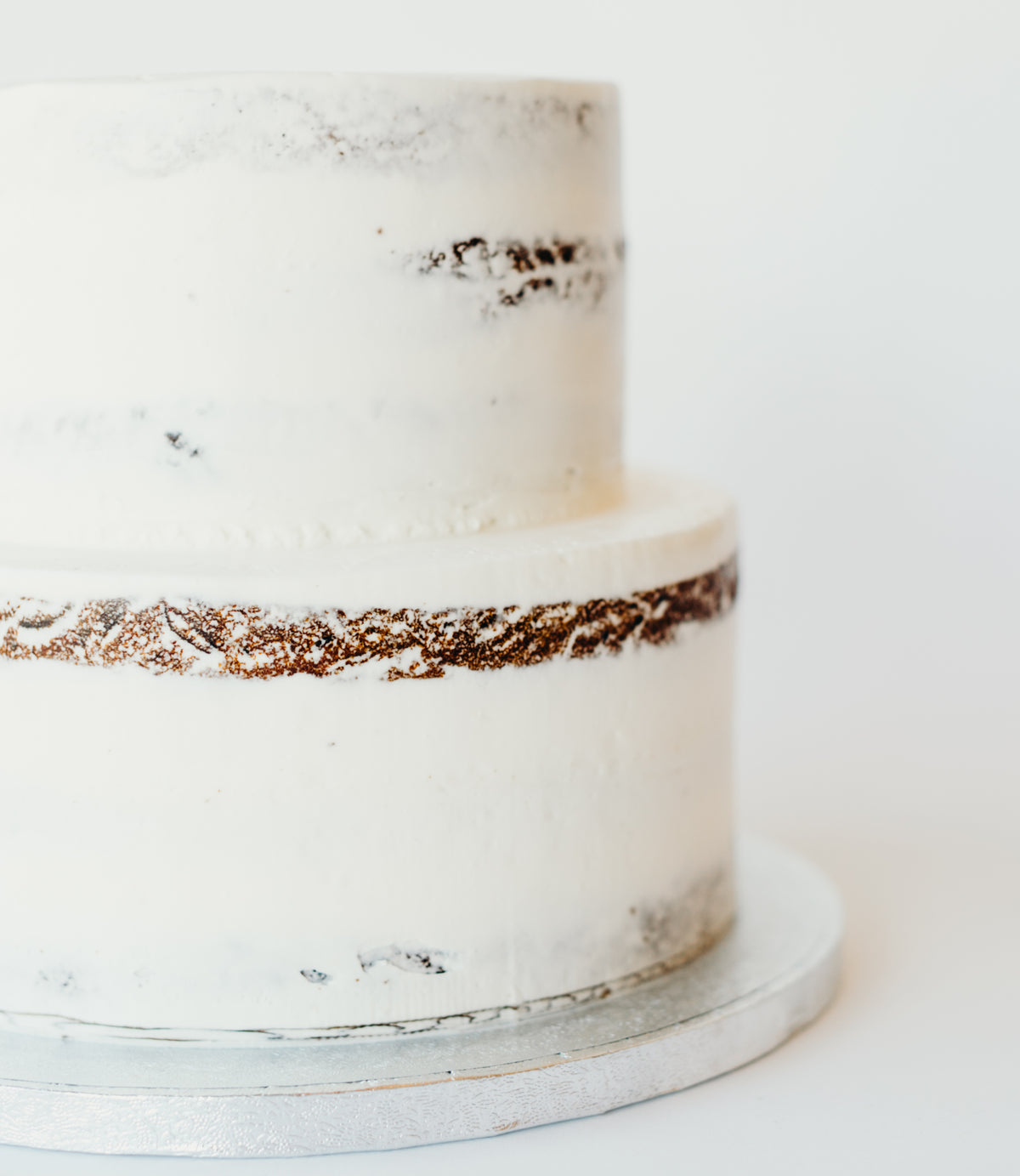 Two-tier semi-naked wedding cake finished with a rustic, lightly frosted look
