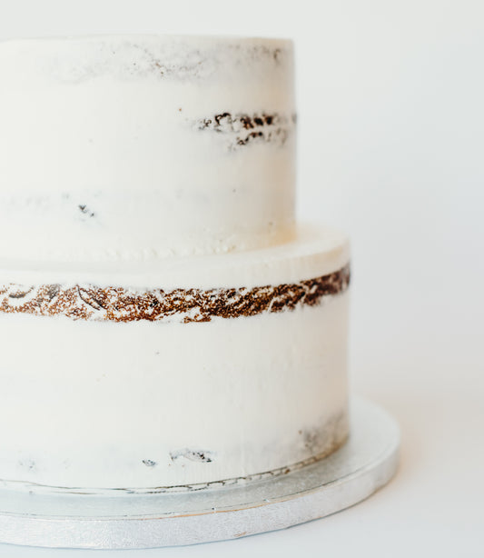 Two-tier semi-naked wedding cake finished with a rustic, lightly frosted look