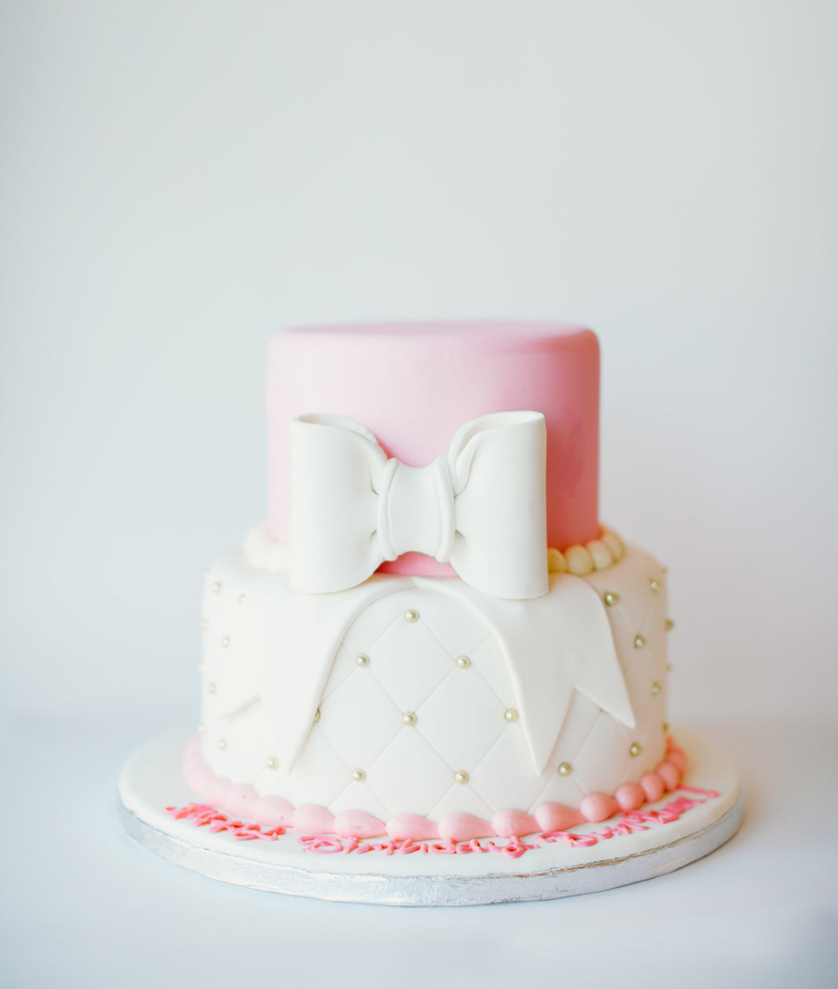 Two-tier quilted fondant cake finished with a pink bow topper