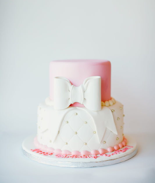 Two-tier quilted fondant cake finished with a pink bow topper