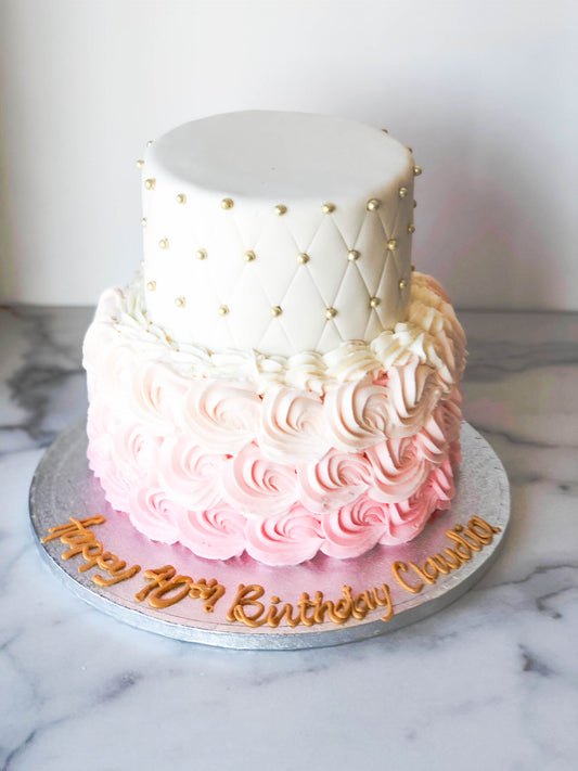 Two-tier cake with quilted fondant detailing and pink and pastel rosettes