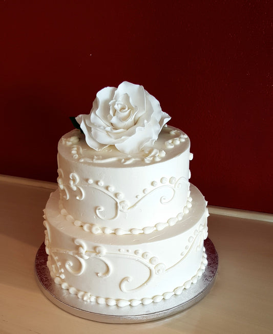 Two-tier cake decorated with scroll piping and florals