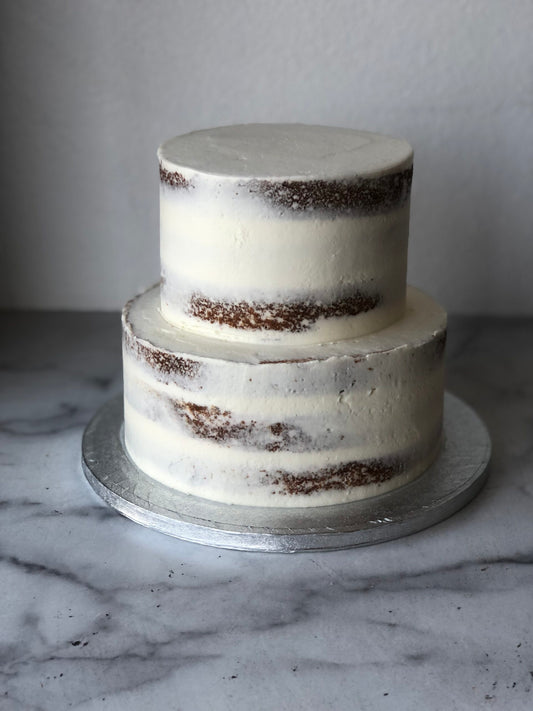 Two-tier semi-naked wedding cake with light buttercream and exposed cake layers