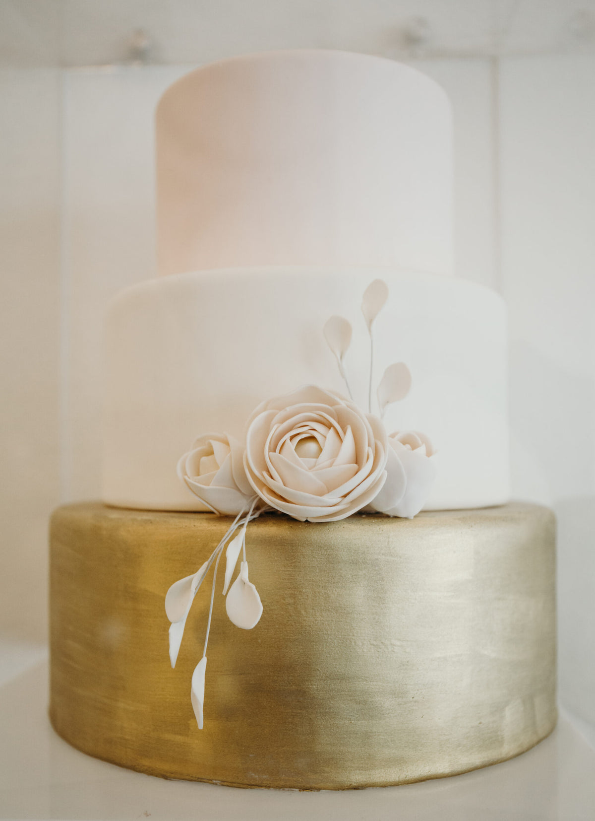 Three-tier cake decorated with gold accents and florals