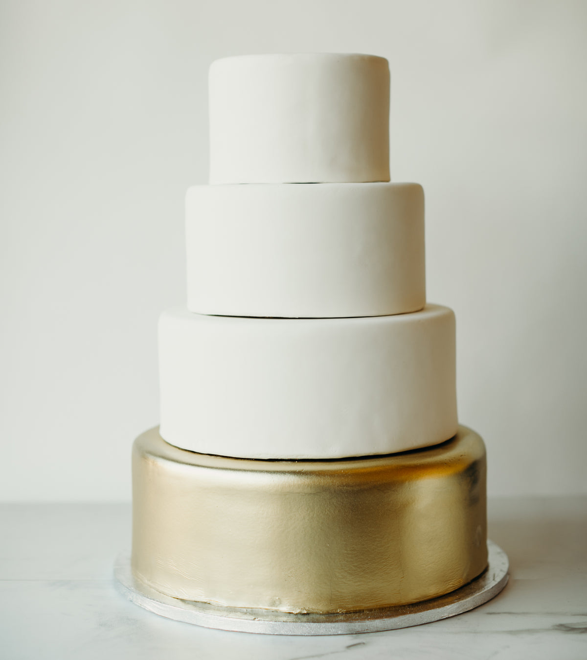 Four-tier cake decorated in white and gold