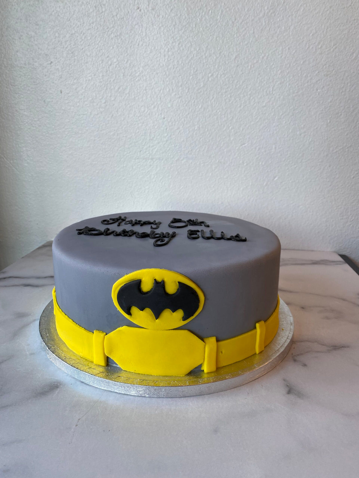 Batman-themed birthday cake with the Batman logo in black and yellow