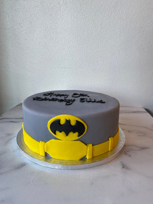 Batman-themed birthday cake with the Batman logo in black and yellow