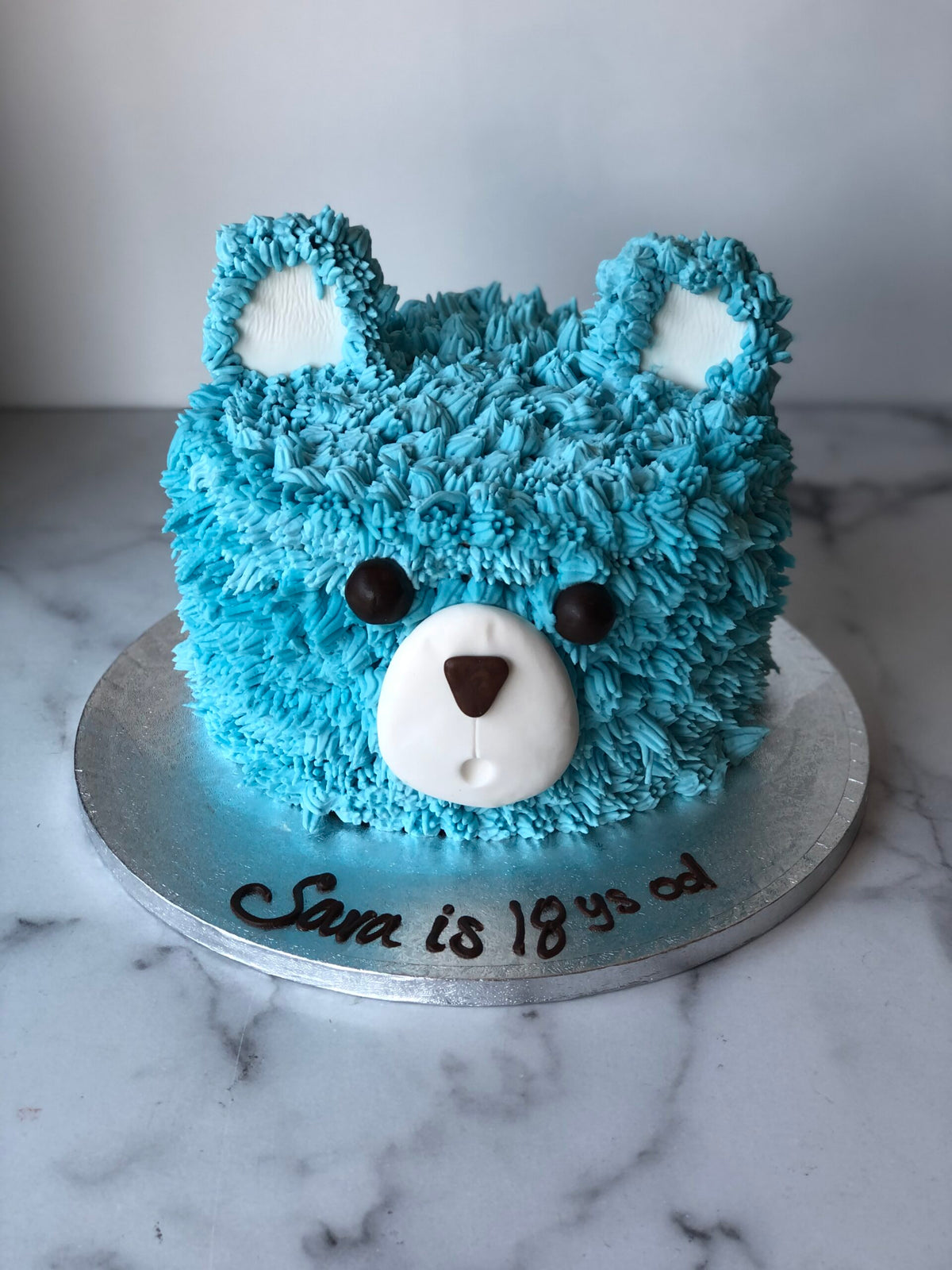 Baby shower cake topped with a blue fondant teddy bear