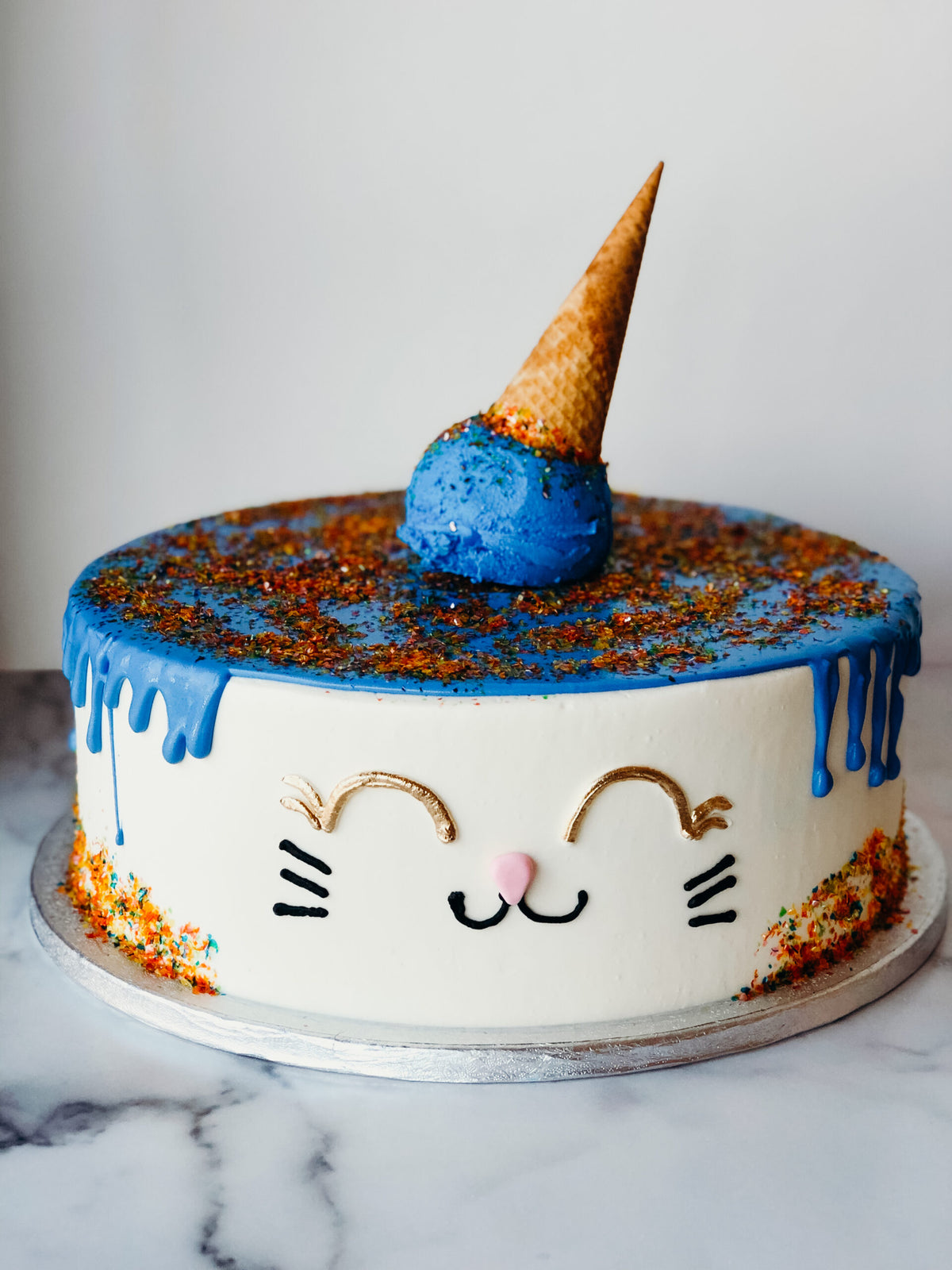 Cake shaped like an ice cream cone with a cat design