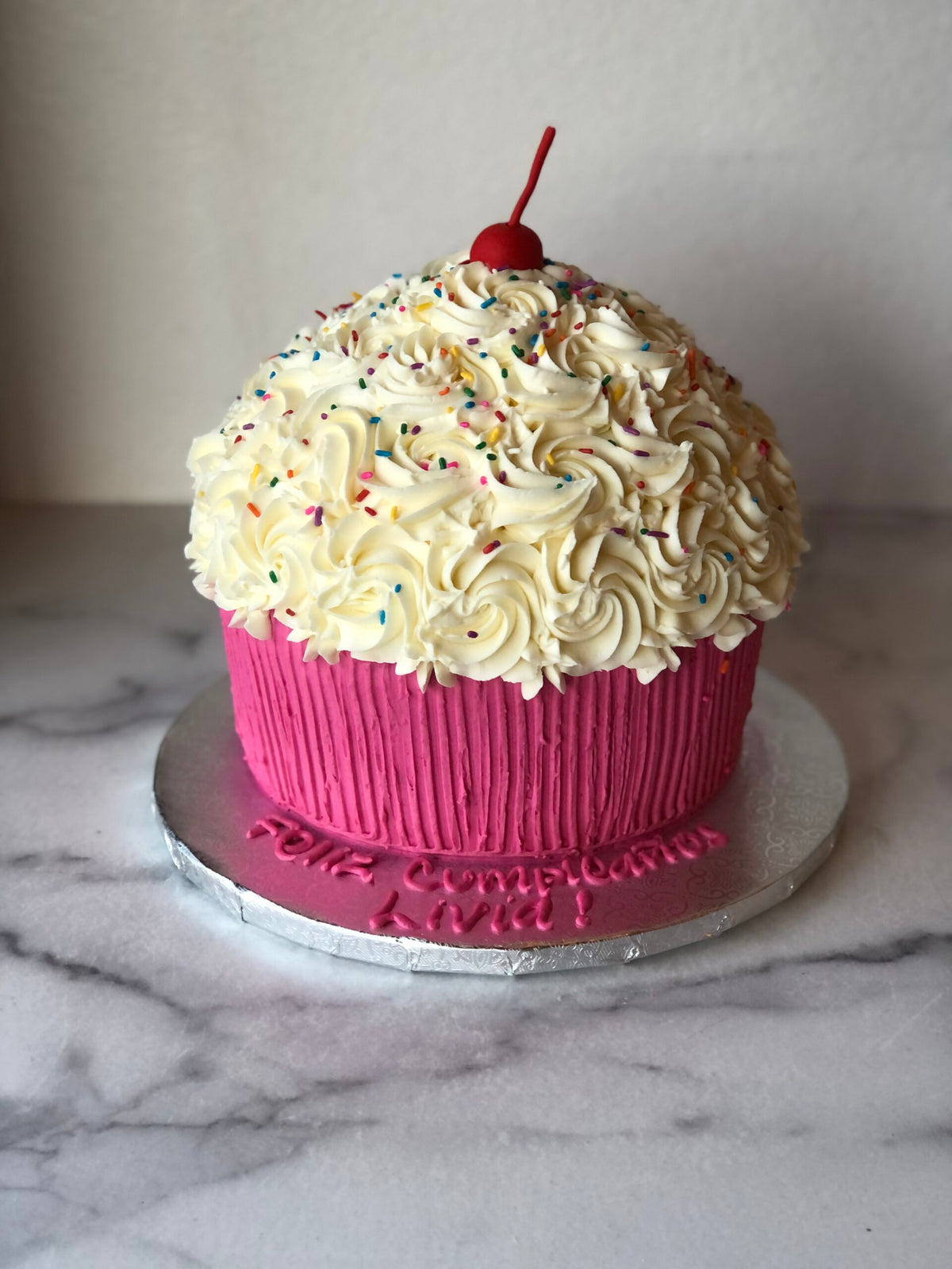 Giant cupcake-shaped birthday cake decorated to look like an oversized cupcake