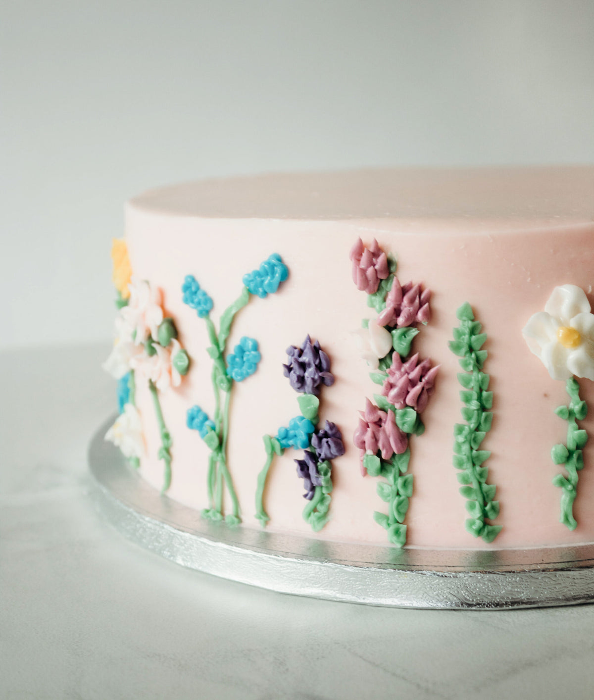 Classic birthday cake with hand-piped floral buttercream detailing on the sides