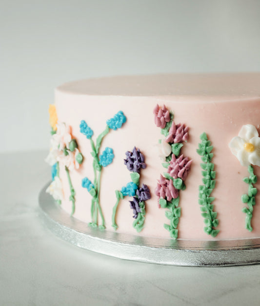 Classic birthday cake with hand-piped floral buttercream detailing on the sides