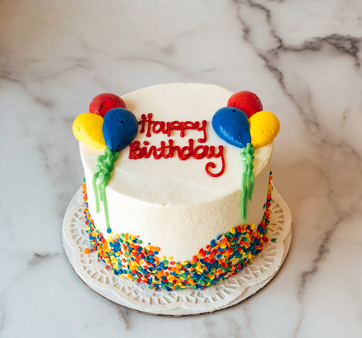 Birthday cake decorated with a cluster of colorful fondant balloons
