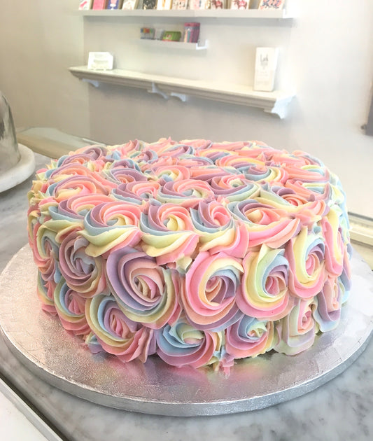Birthday cake covered in pastel rainbow buttercream rosettes