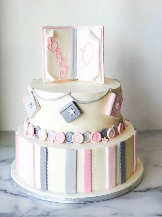 Two-tier baby shower cake decorated with a pink and grey storybook theme