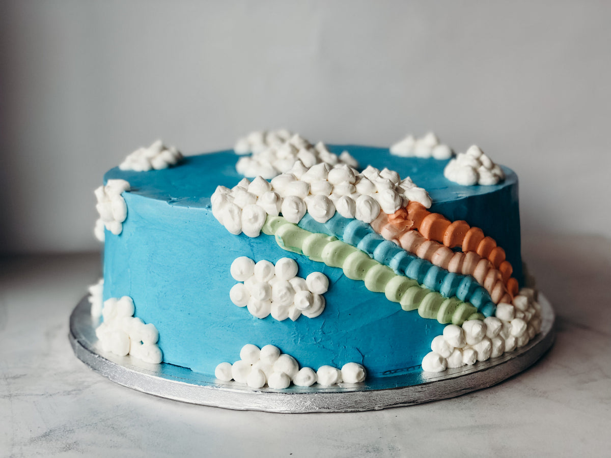 Cake decorated with a rainbow and clouds design