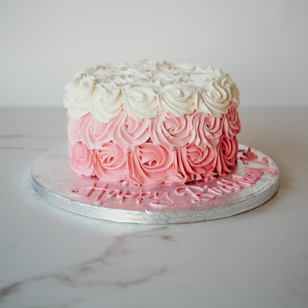 Cake decorated in an ombre pink rosette design, from pale to deep pink