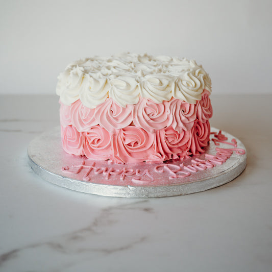 Cake decorated in an ombre pink rosette design, from pale to deep pink