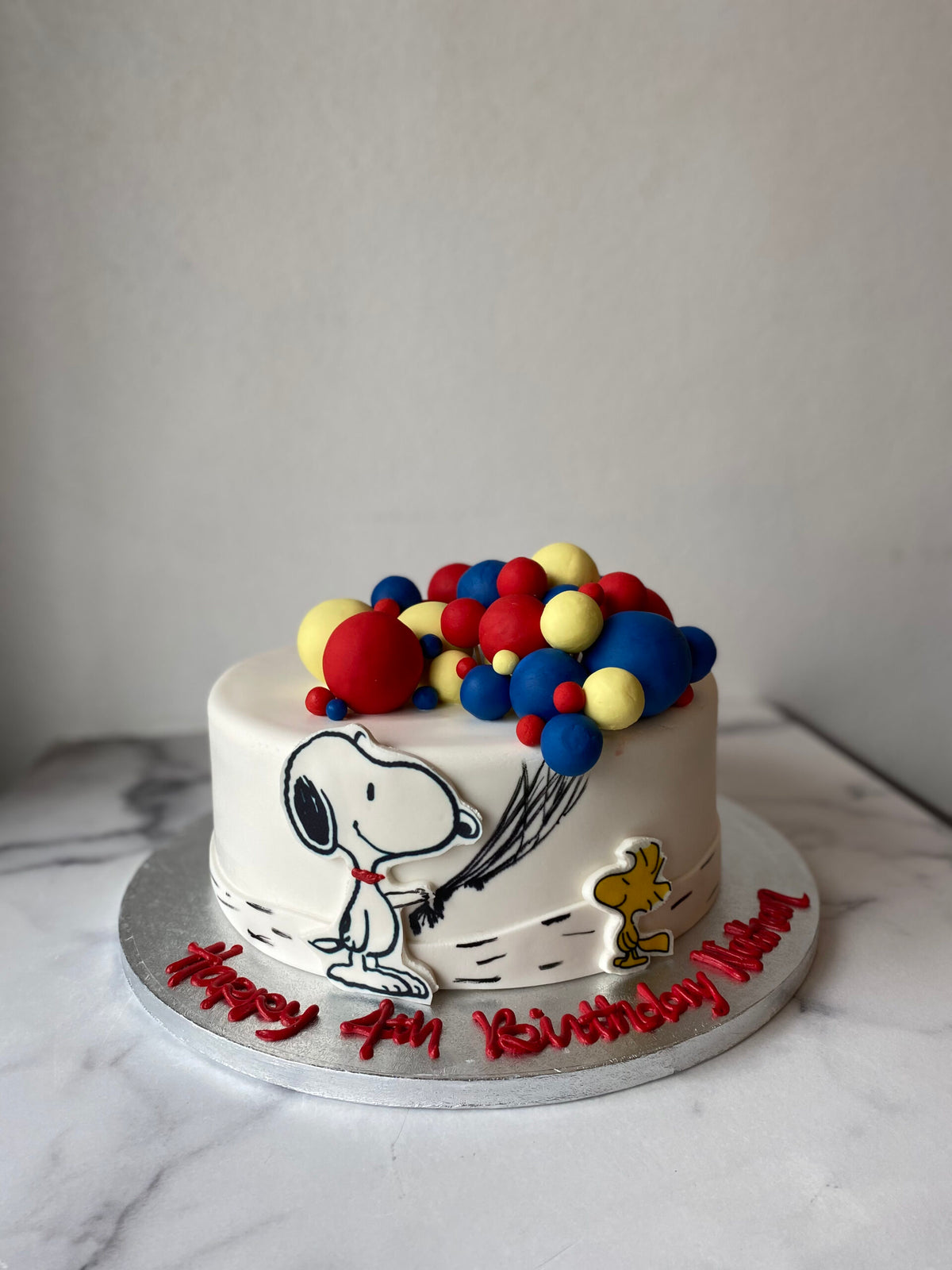 Snoopy-themed birthday cake decorated with colorful fondant balloons
