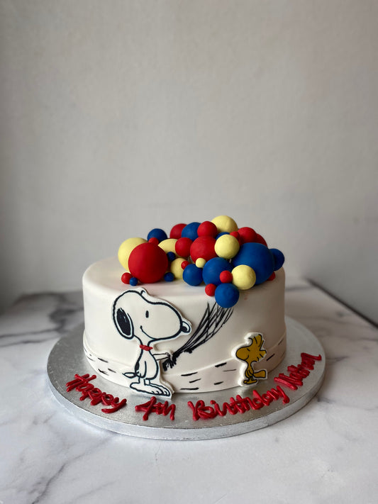 Snoopy-themed birthday cake decorated with colorful fondant balloons