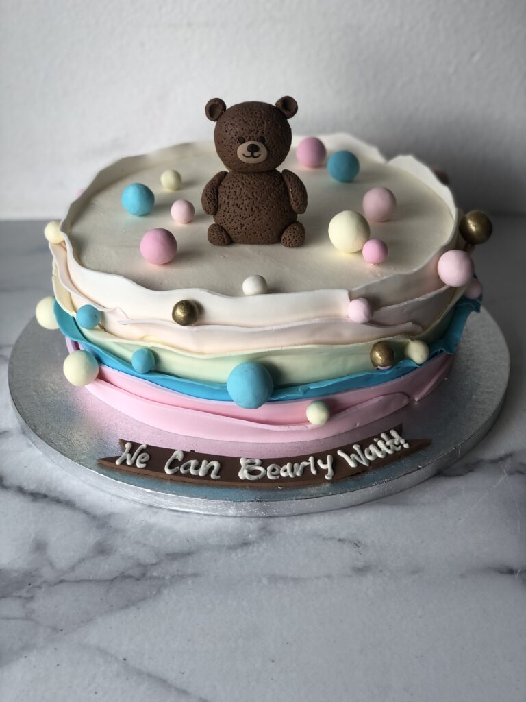 Baby shower cake with a teddy bear theme and "We Can Bearly Wait" design