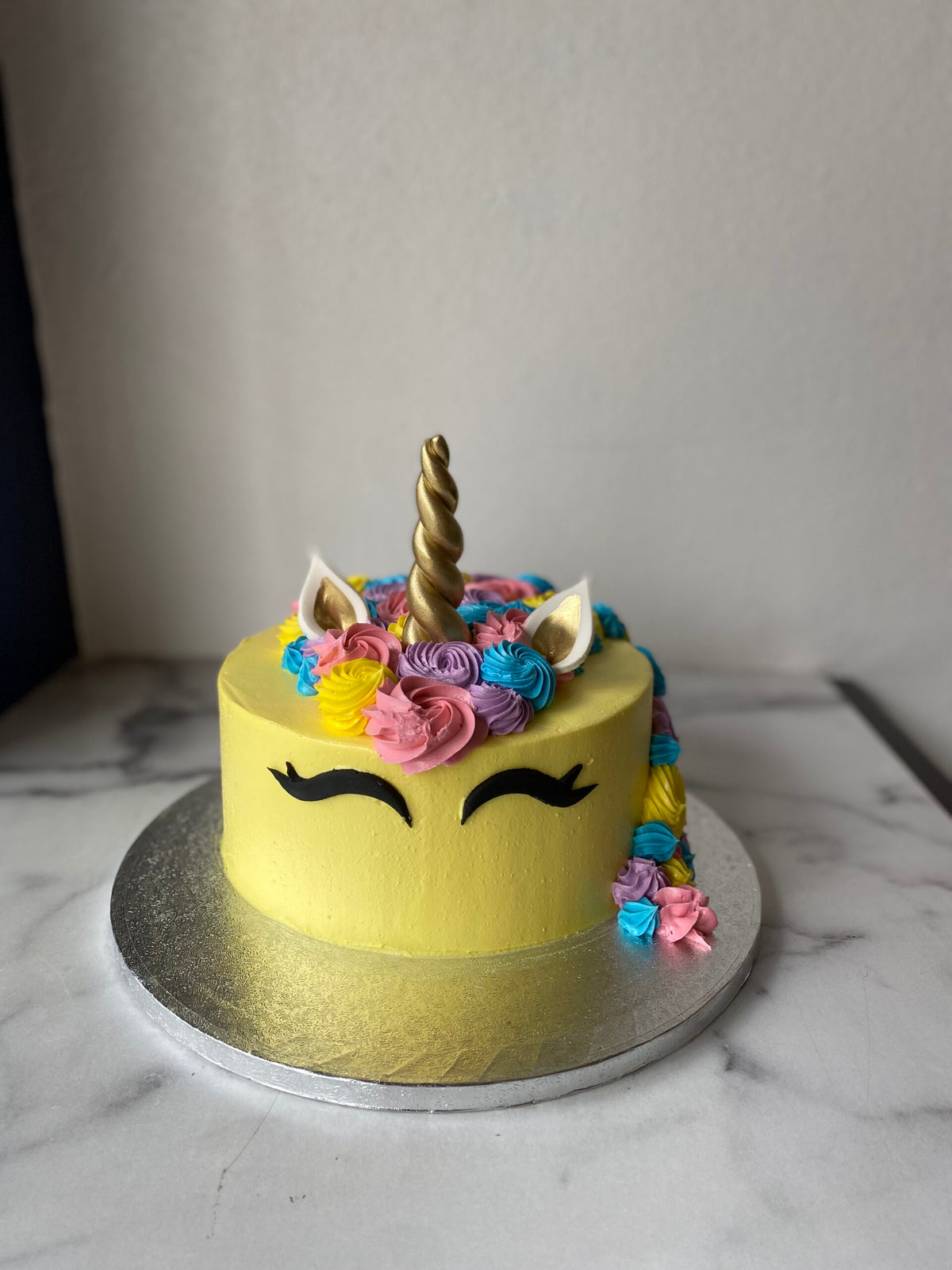 Cake decorated with a yellow unicorn theme