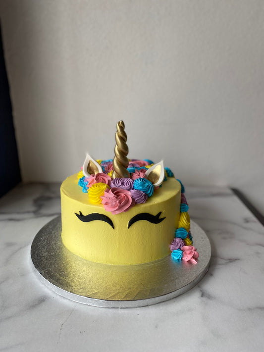 Cake decorated with a yellow unicorn theme