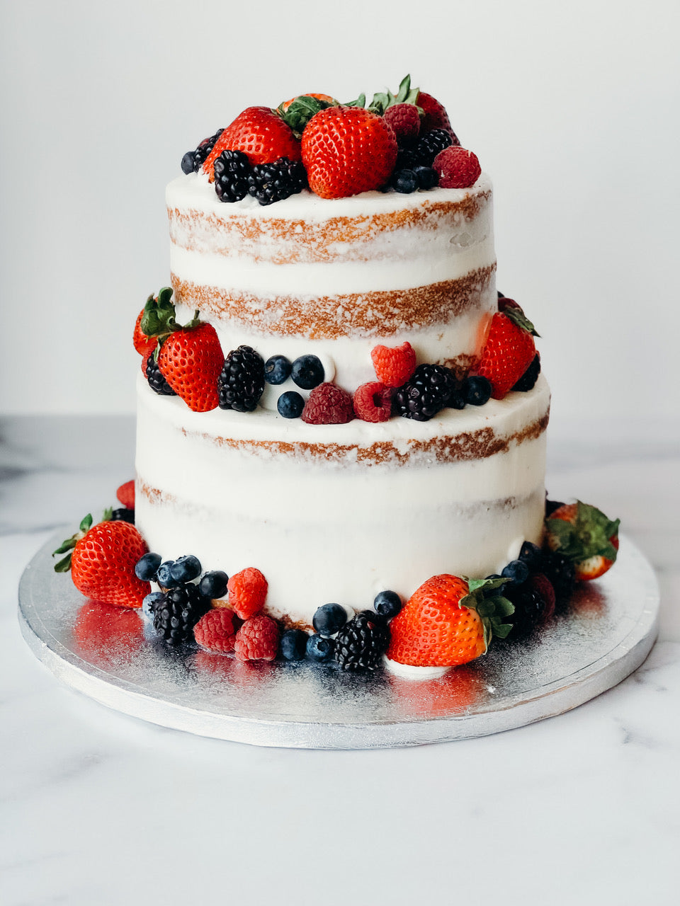 Two-tier semi-naked berry shortcake with fresh berries and whipped cream