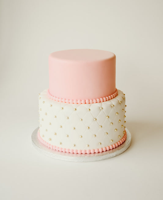 Two-tier birthday cake in pink and white with a soft, classic finish