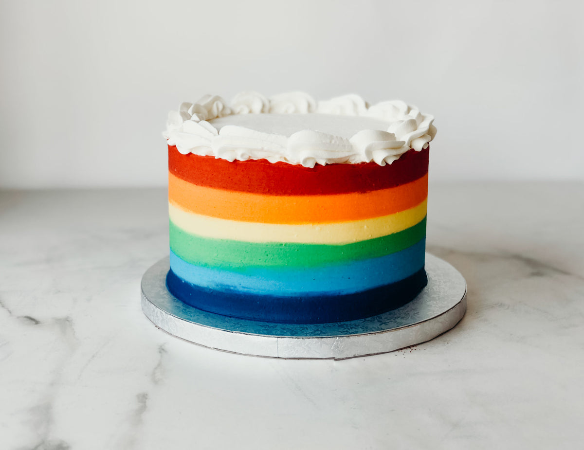 Birthday cake decorated with bold rainbow-striped buttercream