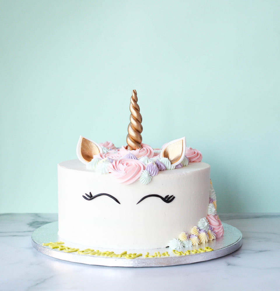 Unicorn-themed birthday cake with a fondant horn, ears, and pastel mane
