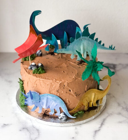 brown cake with dinosaur cutouts on it